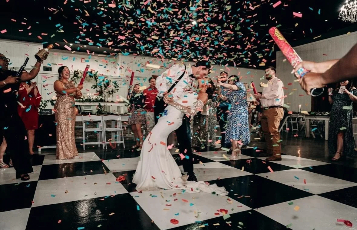 Bride and groom kissing on the dance floor as confetti falls